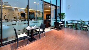 A modern indoor area with glass walls, wooden flooring, and several tables and chairs.