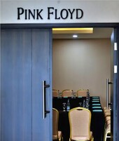 Kokoushuone, jossa on kokouksiin katettu pöytä, tuoleja ja sen yläpuolella oleva kyltti, jossa lukee: ”PINK FLOYD”.