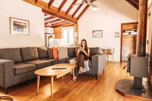 Una sala de estar acogedora con techo de madera, un sofá, una mesa de centro y una chimenea.