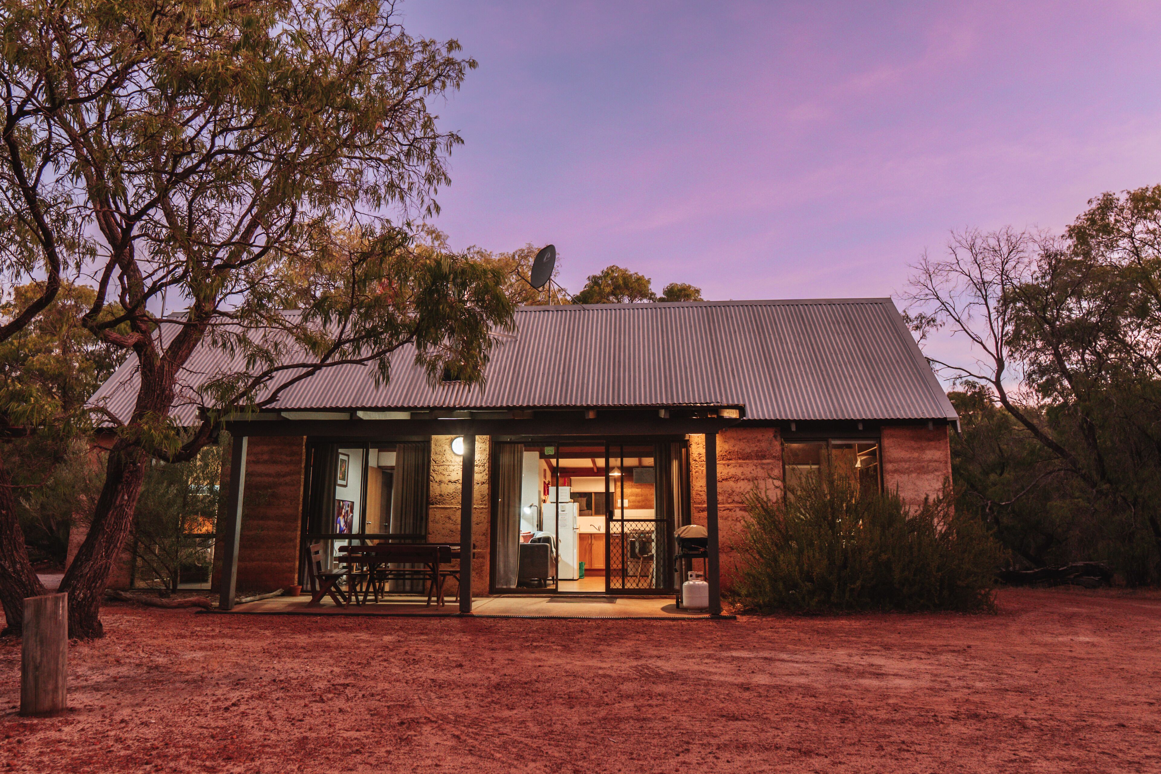 A rustic house with a metal roof, large glass doors, and a visible kitchen area.