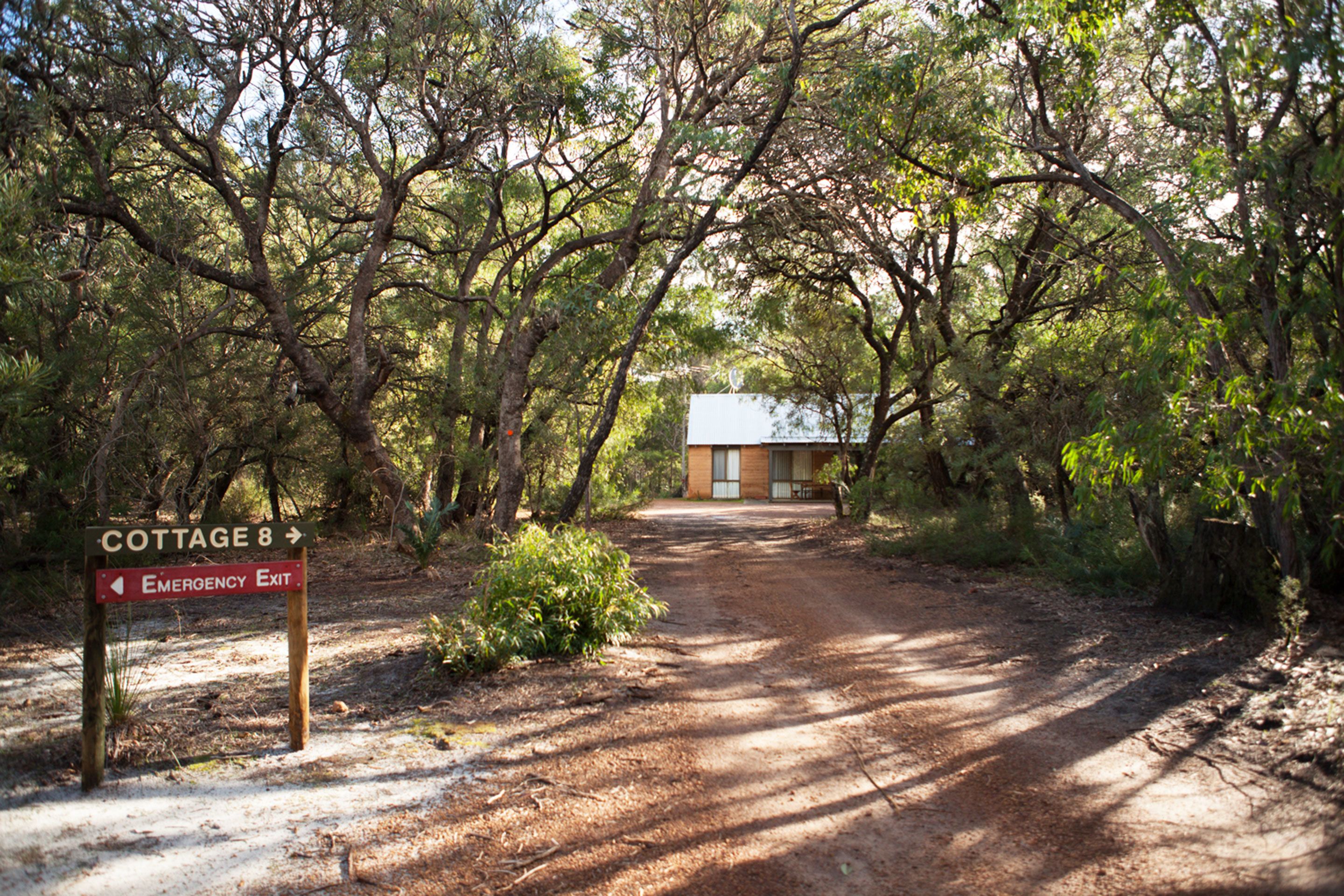 A dirt path leading to a building labeled 'COTTAGE 8' with an 'Emergency Exit' sign.