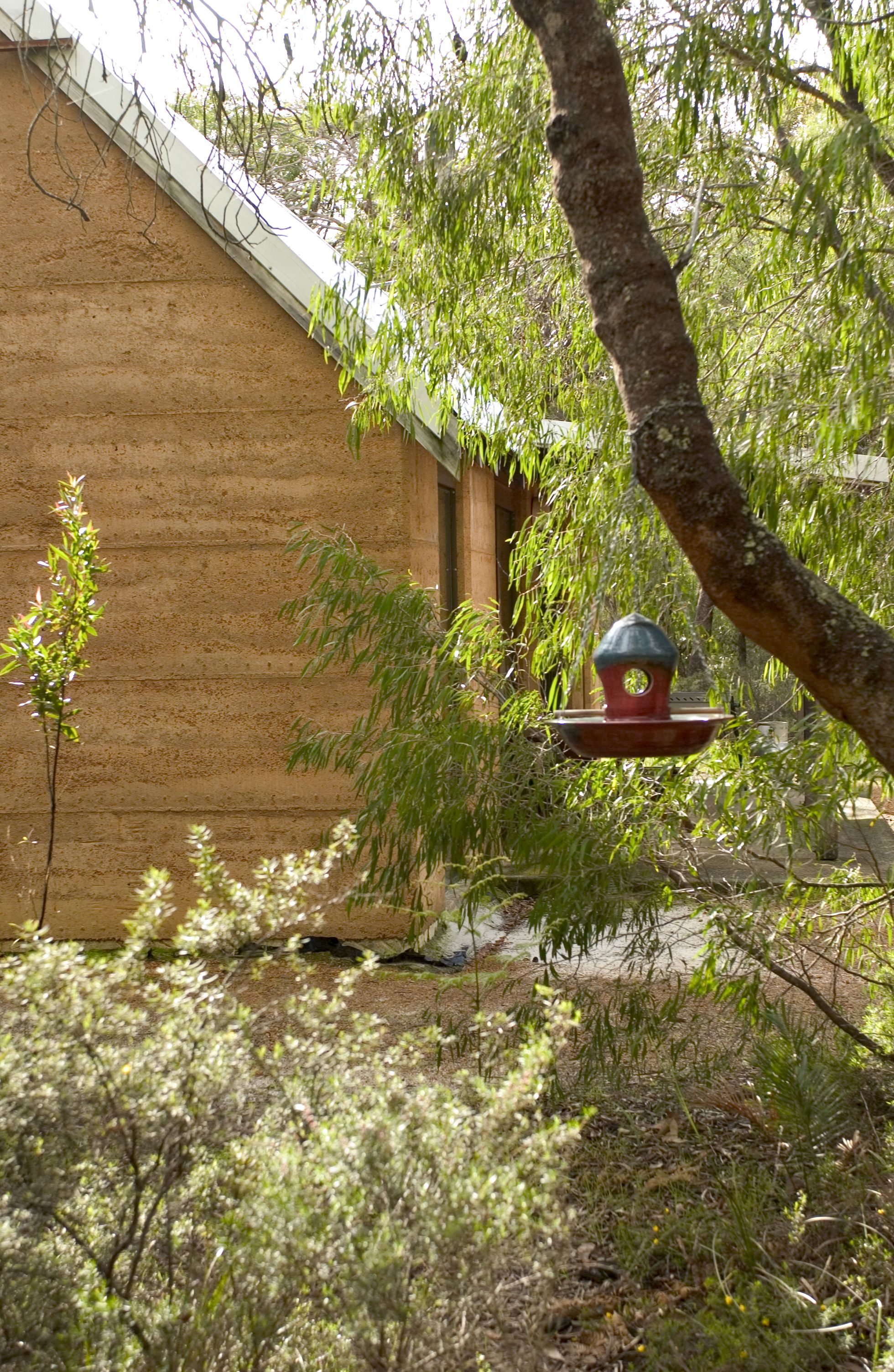 Une cabane en bois avec une mangeoire à oiseaux devant.