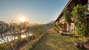A pathway leading to a building with a view of the water and hills. - Sanctuary Pakbeng Lodge (Pakbeng)