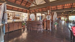 A spacious indoor area with a wooden bar and seating, large windows, and a high ceiling. - Sanctuary Pakbeng Lodge (Pakbeng)