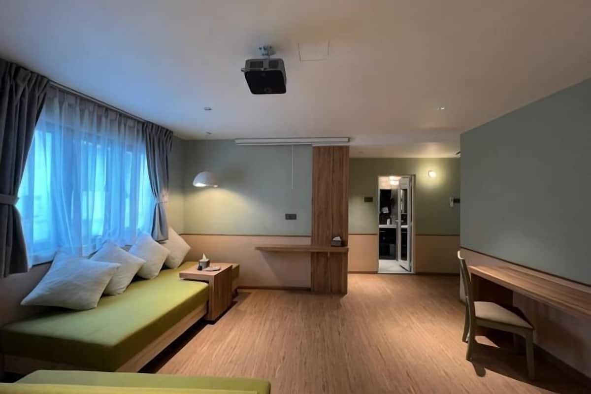 Une chambre d’hôtel équipée d’un lit, d’un bureau, d’une chaise, d’un miroir et d’une porte donnant accès à une salle de bain.