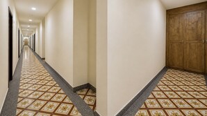 A hotel hallway with a patterned floor, a wooden door, and a long corridor. - OYO Swiss Hotel Heritage Boutique Melaka (Malacca City)