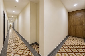 A hotel hallway with a patterned floor, a wooden door, and a long corridor. - OYO Swiss Hotel Heritage Boutique Melaka (Malacca City)