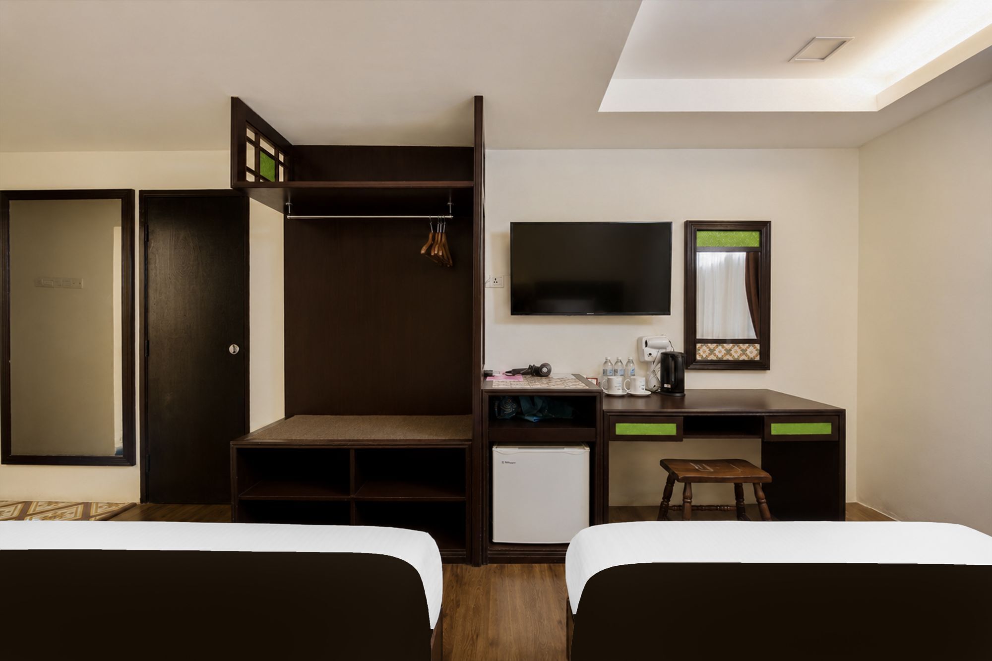 A hotel room with a bed, a desk, a wardrobe, a television, and a mirror.