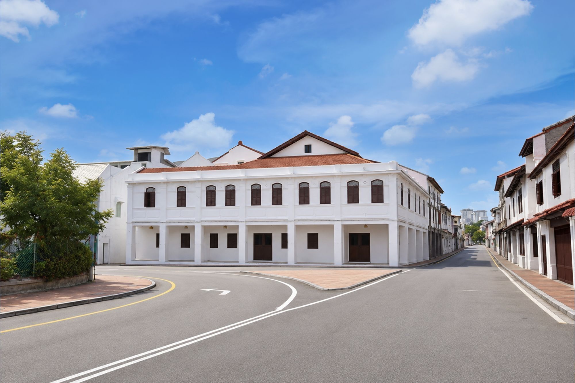 A street with a white building with multiple windows and a red roof.