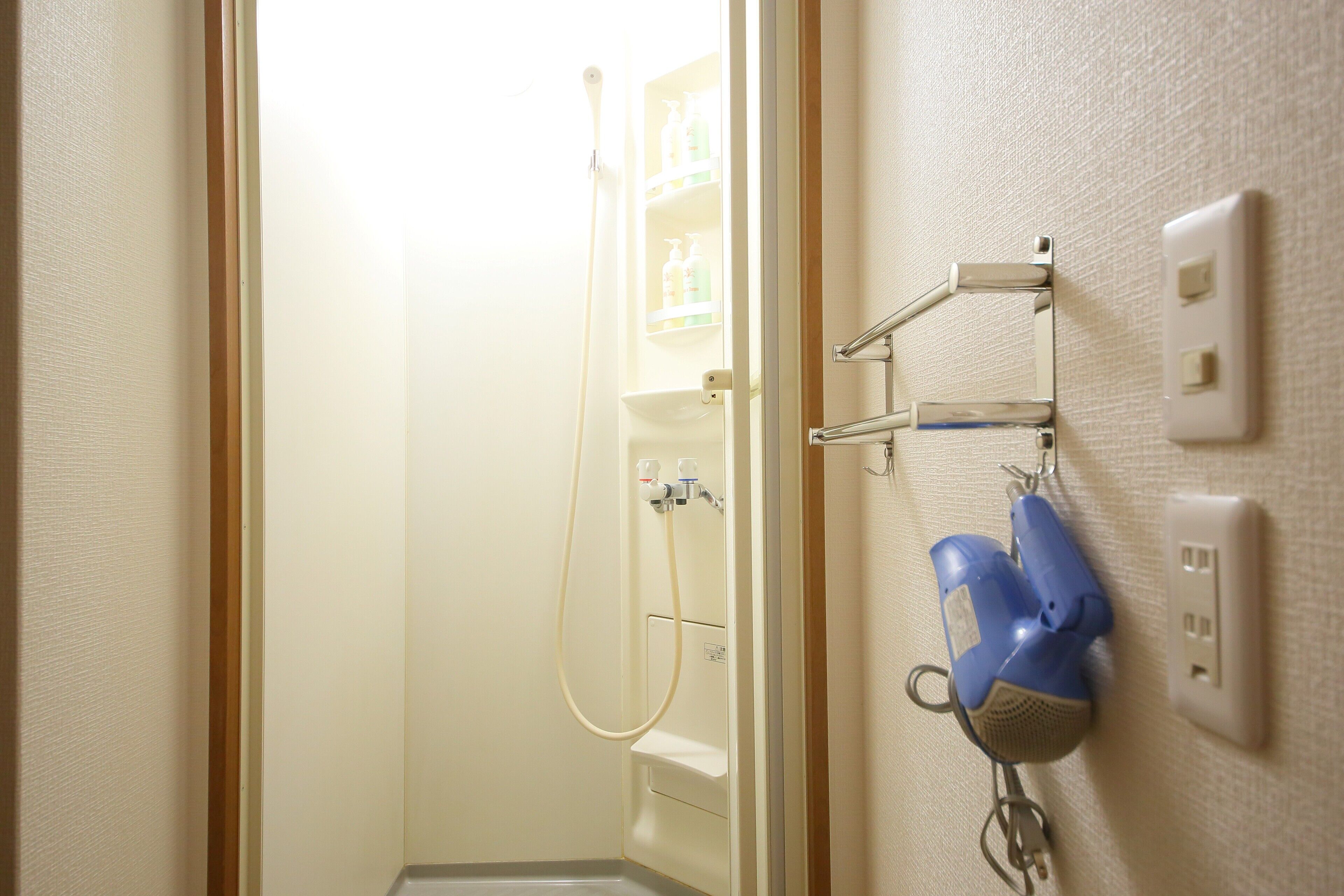Een badkamer met een douche, een handdoekhouder en een stopcontact op de muur.