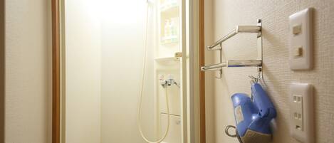 Een badkamer met een douche, een handdoekhouder en een stopcontact op de muur.