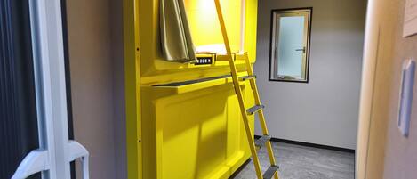 A room with a yellow cabinet, a ladder, and a window.