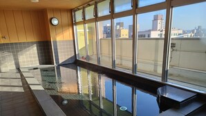 An indoor swimming pool with clear glass walls, a tiled floor, and a view of the cityscape through the windows. - Shin-Imamiya Hotel (Osaka)