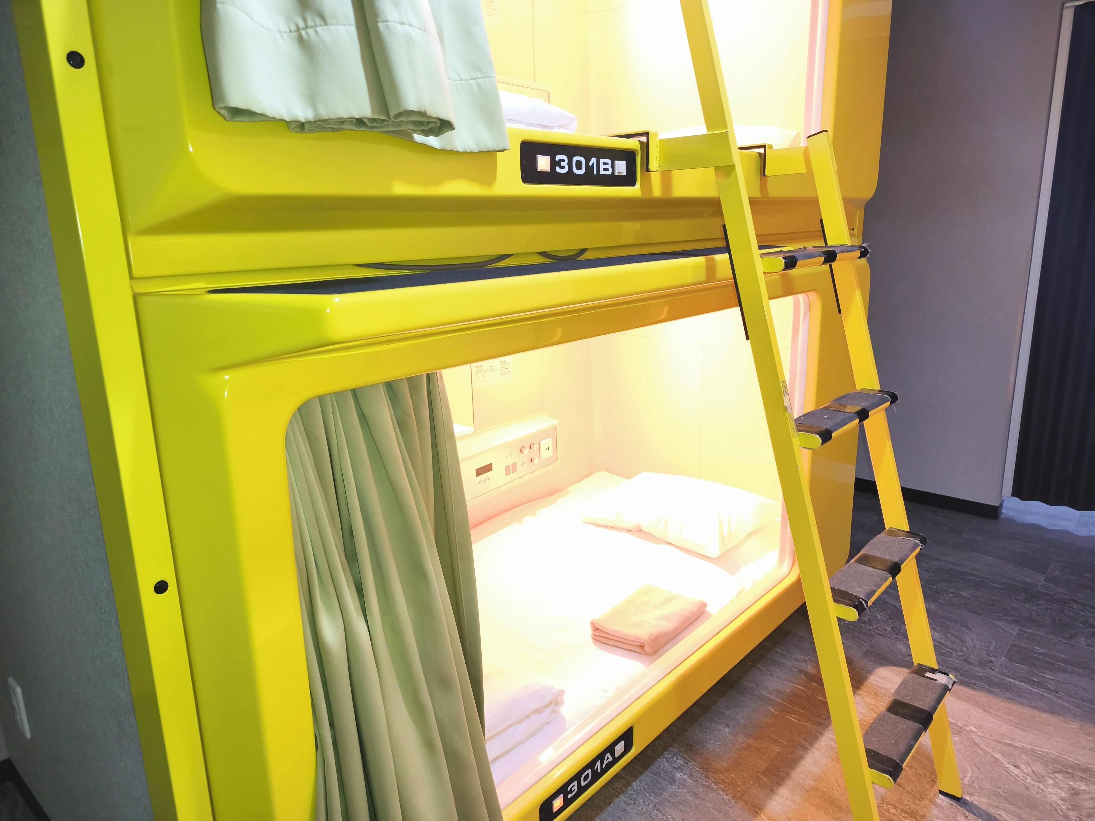 A yellow bunk bed with a ladder, a small bedside table, and a nightstand.