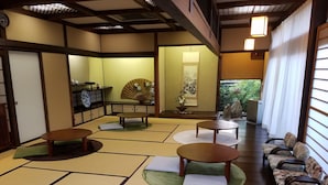 A traditional Japanese room with tatami flooring, low tables, and a sofa. - Sansou Tanaka (Yufu)