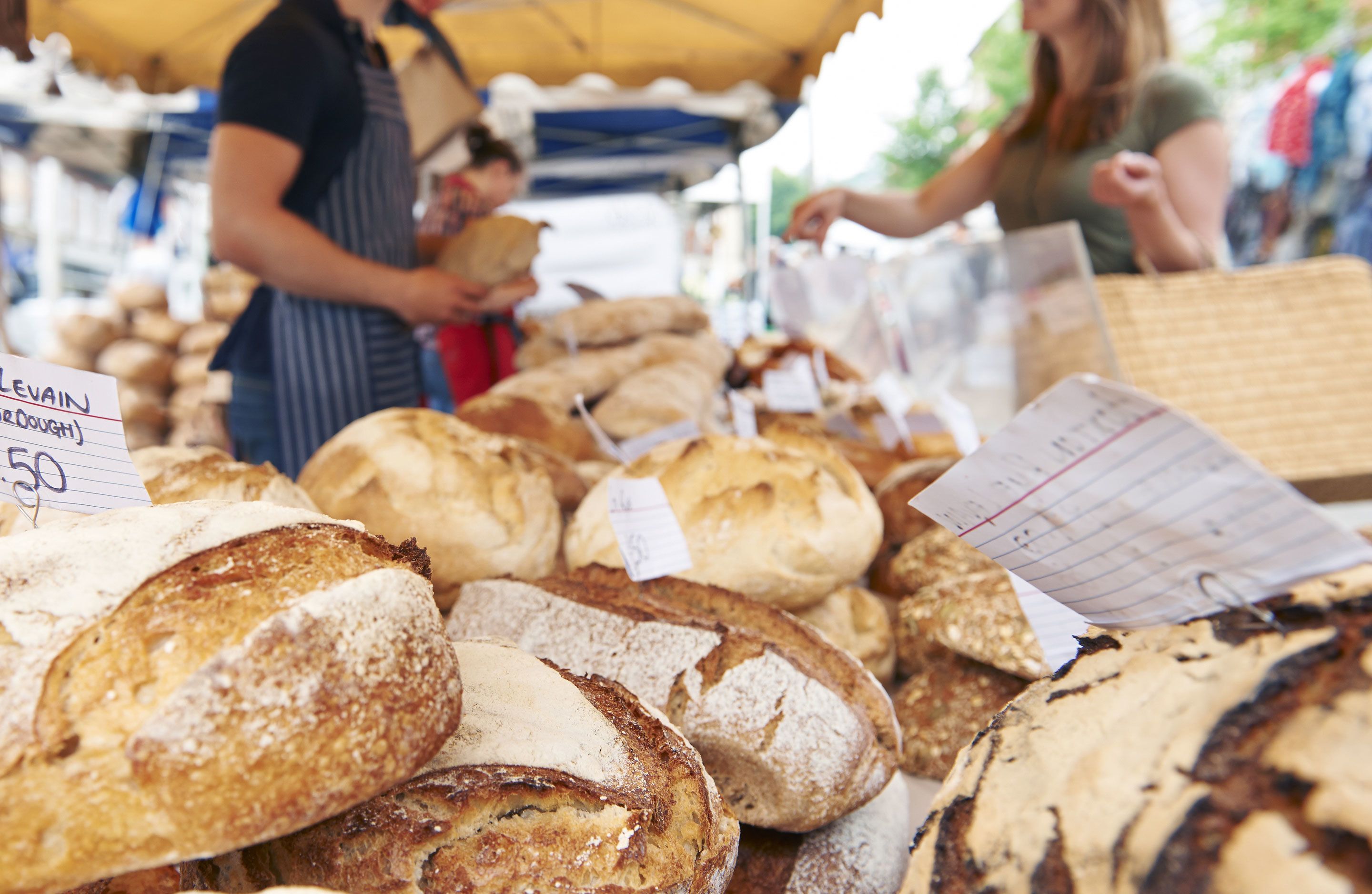 Une variété de pains et de viennoiseries exposés sur un étal de marché.