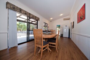 A dining area with a round table, two wooden chairs, and a view of the outdoors through glass doors.