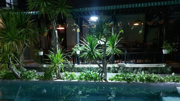 A pool area with tiled flooring, surrounded by various potted plants and trees. - Starfruit Villa Hoi An (Da Nang)
