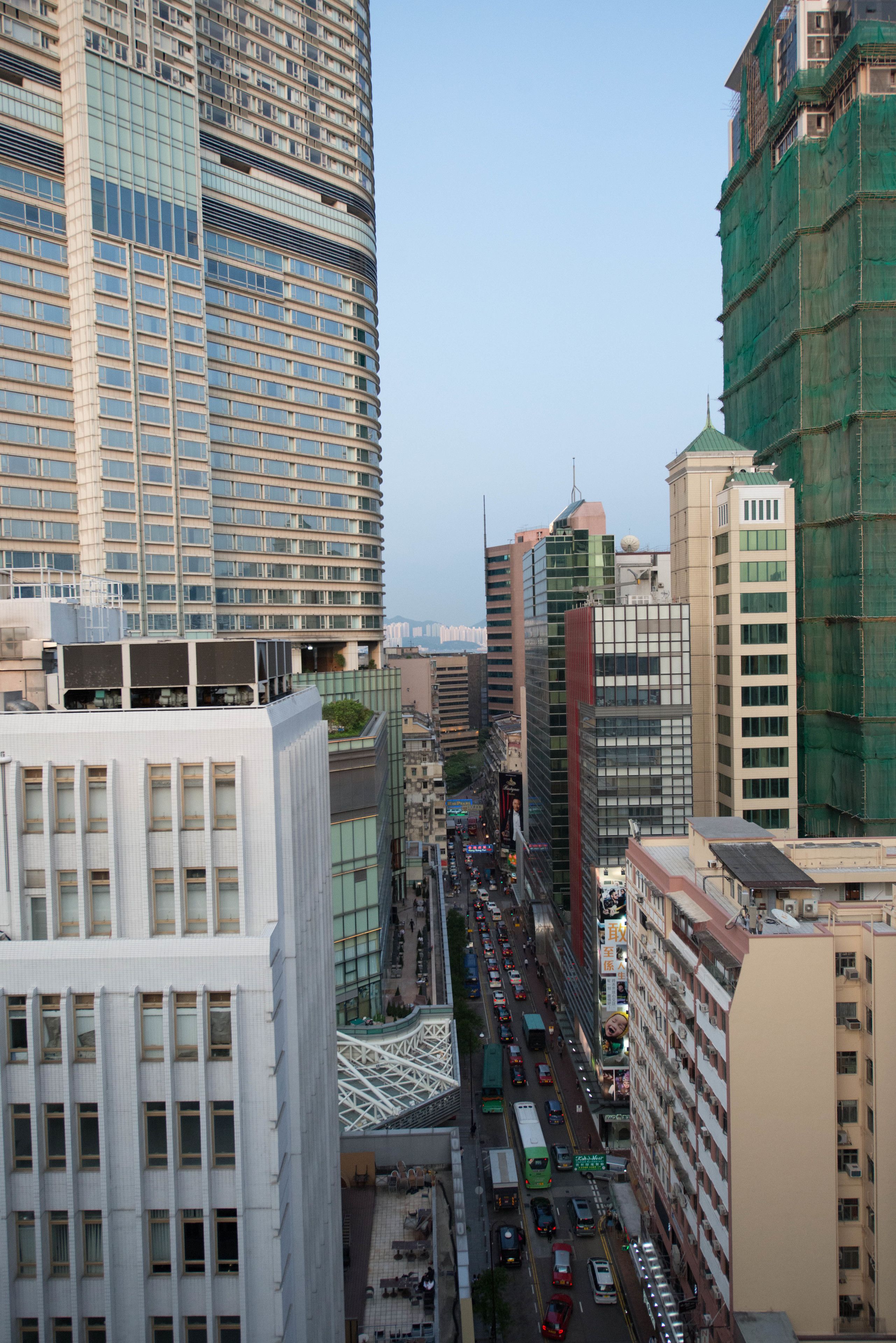 A cityscape with tall buildings, a busy street, and a pedestrian walkway.