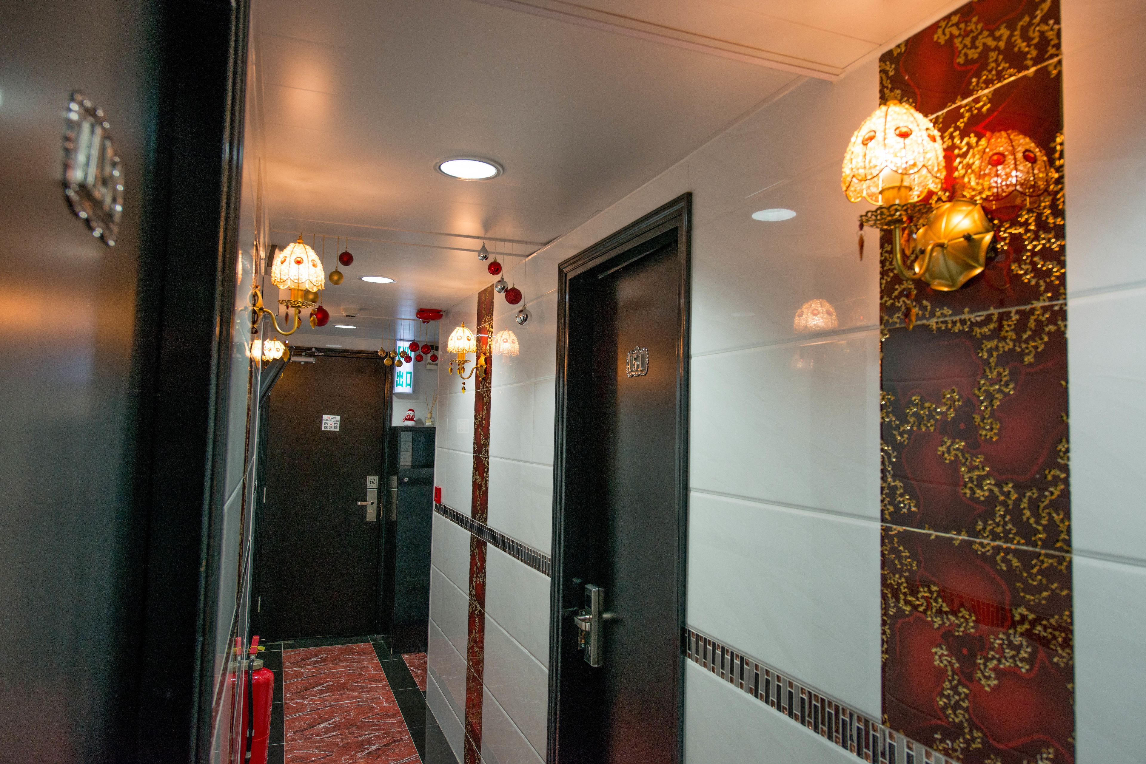 Un couloir avec un tapis rouge, un extincteur et une porte ornée d’un décor mural.