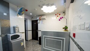 A modern hotel bathroom with a marble floor, a microwave, a refrigerator, a sink, and a shower area.