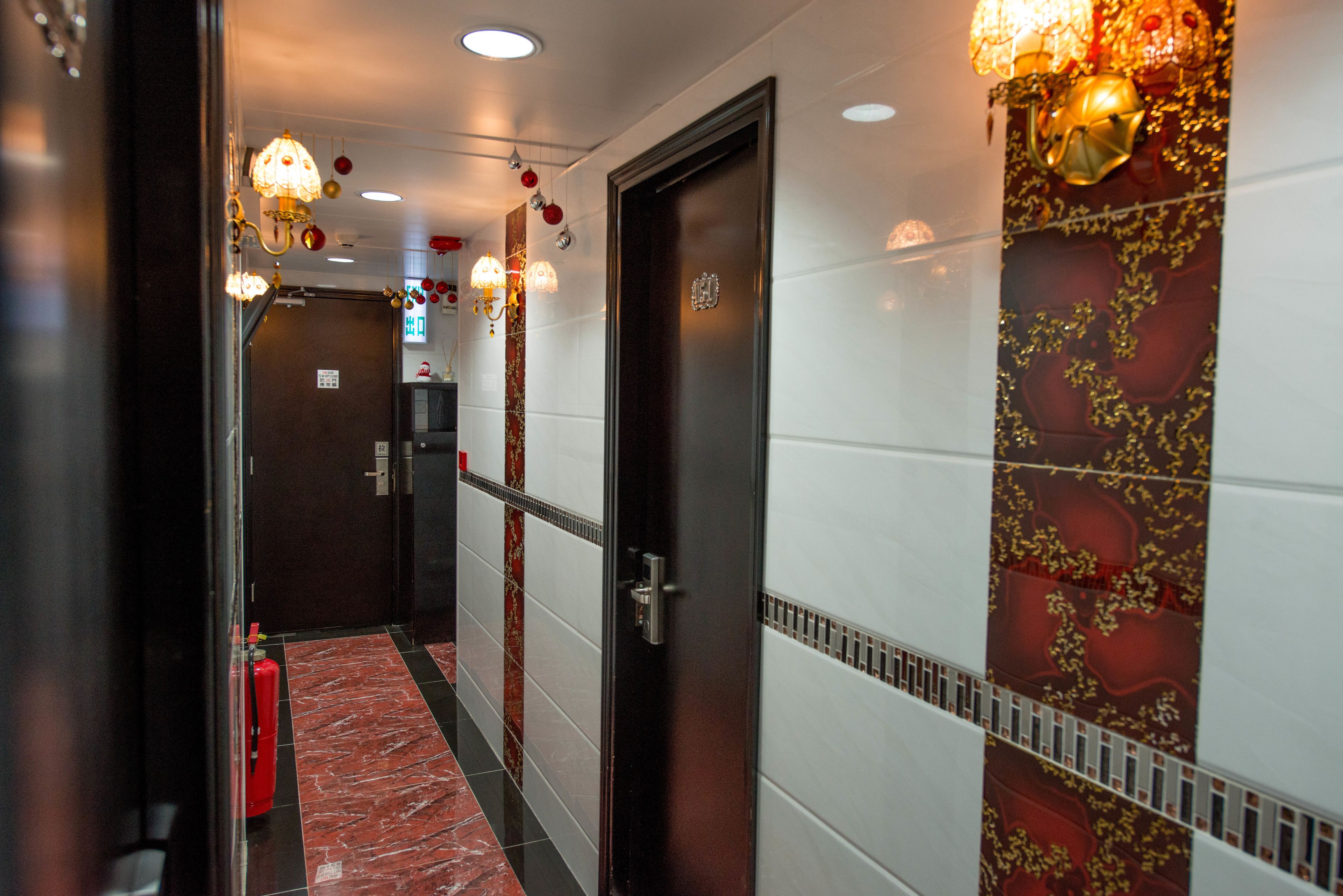 A hotel corridor with a fire extinguisher, a door, and decorative wall lights.