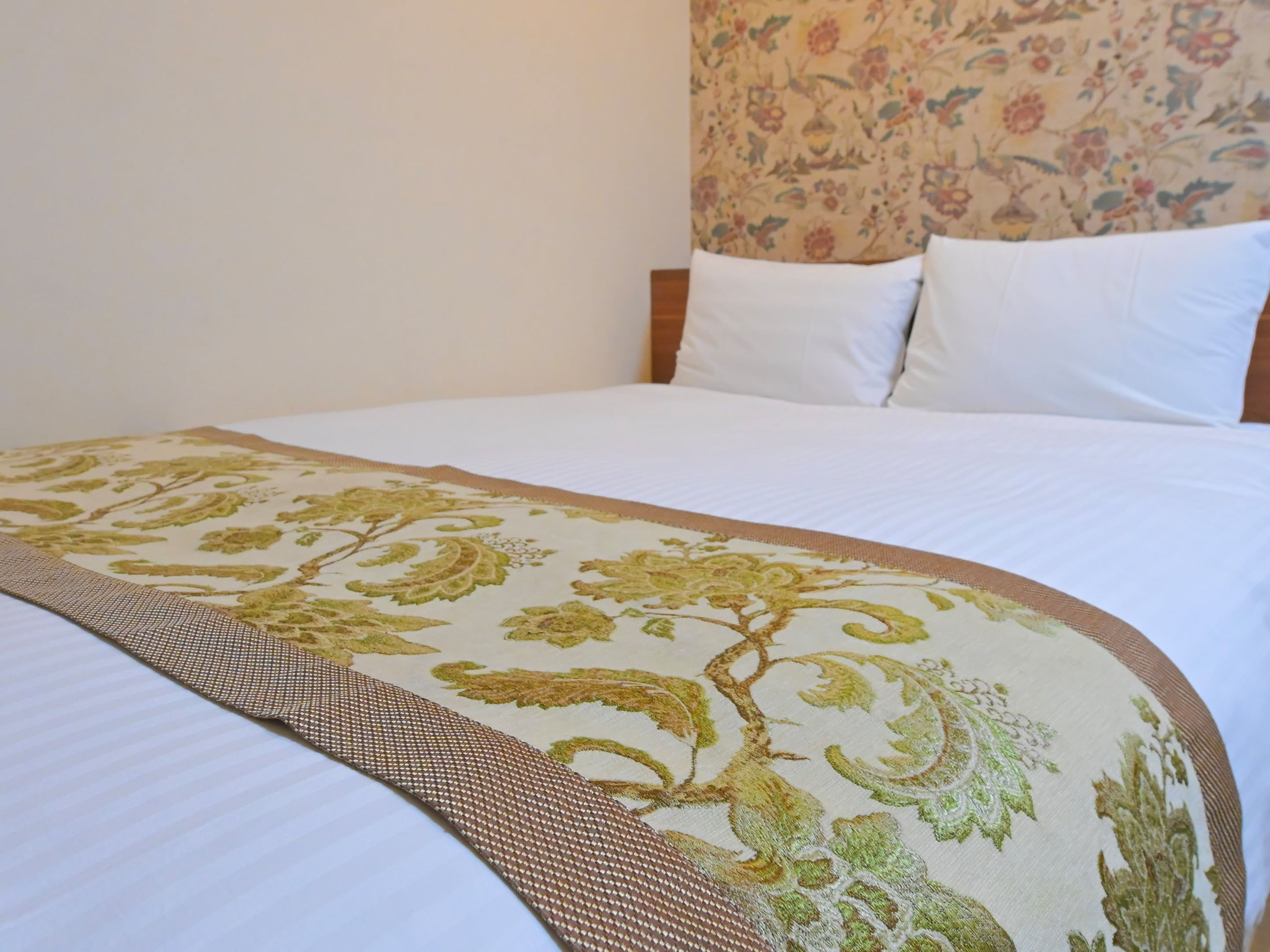 Una cama con colcha estampada con motivos florales y un detalle en marrón.