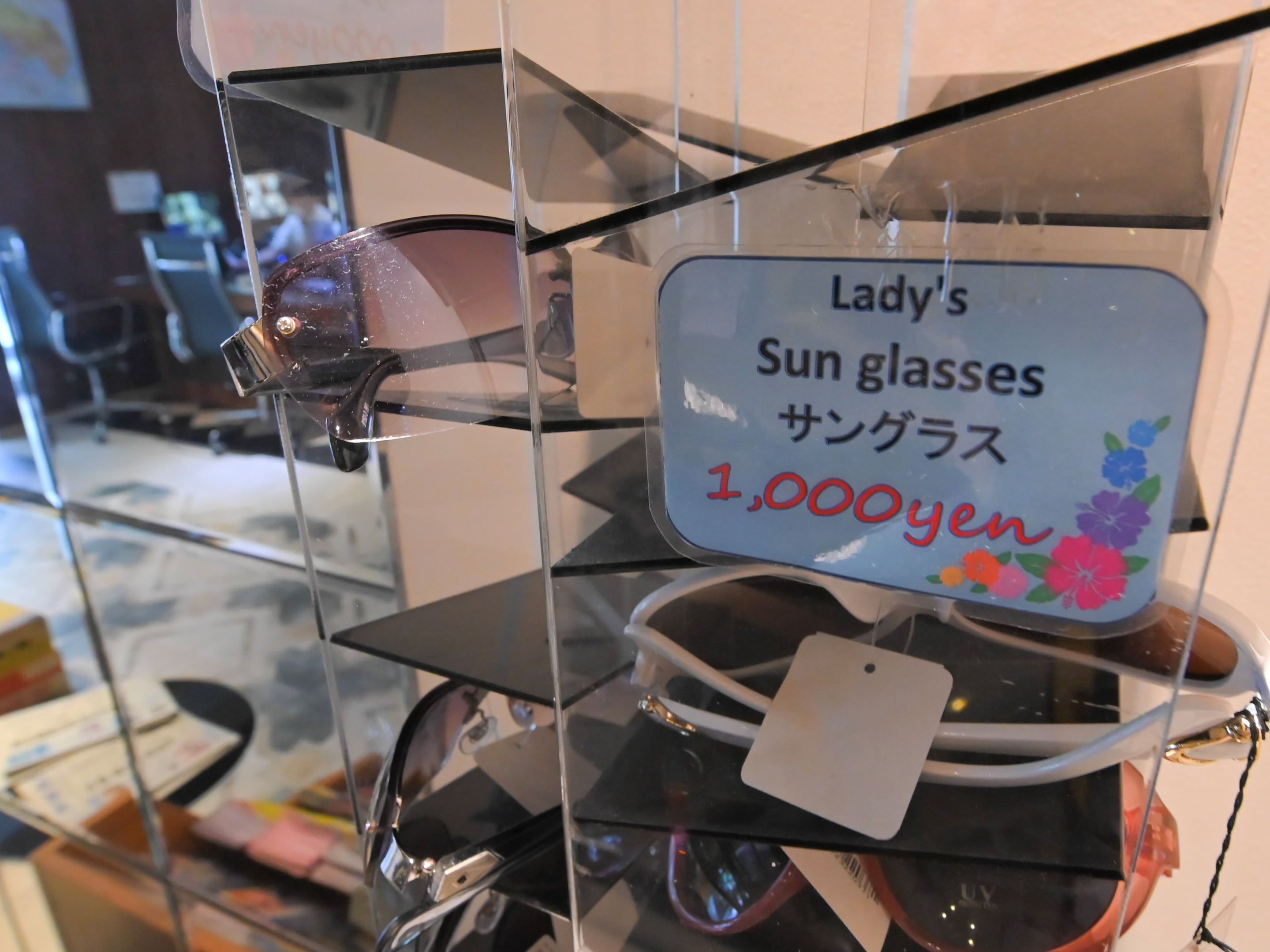 A display of sunglasses with a sign indicating a price of 1,000 yen.