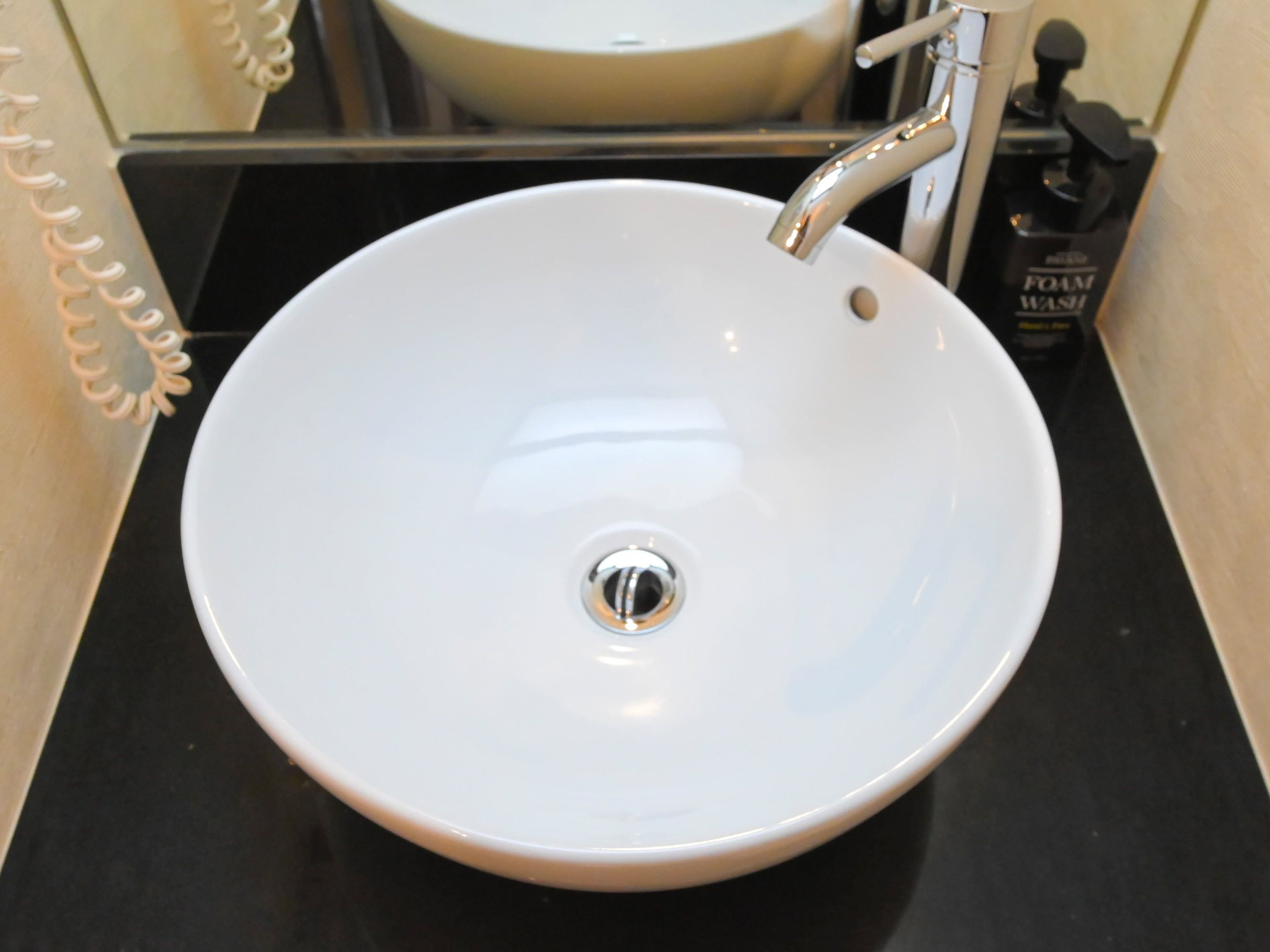 A white ceramic sink with a single faucet, positioned on a black countertop.