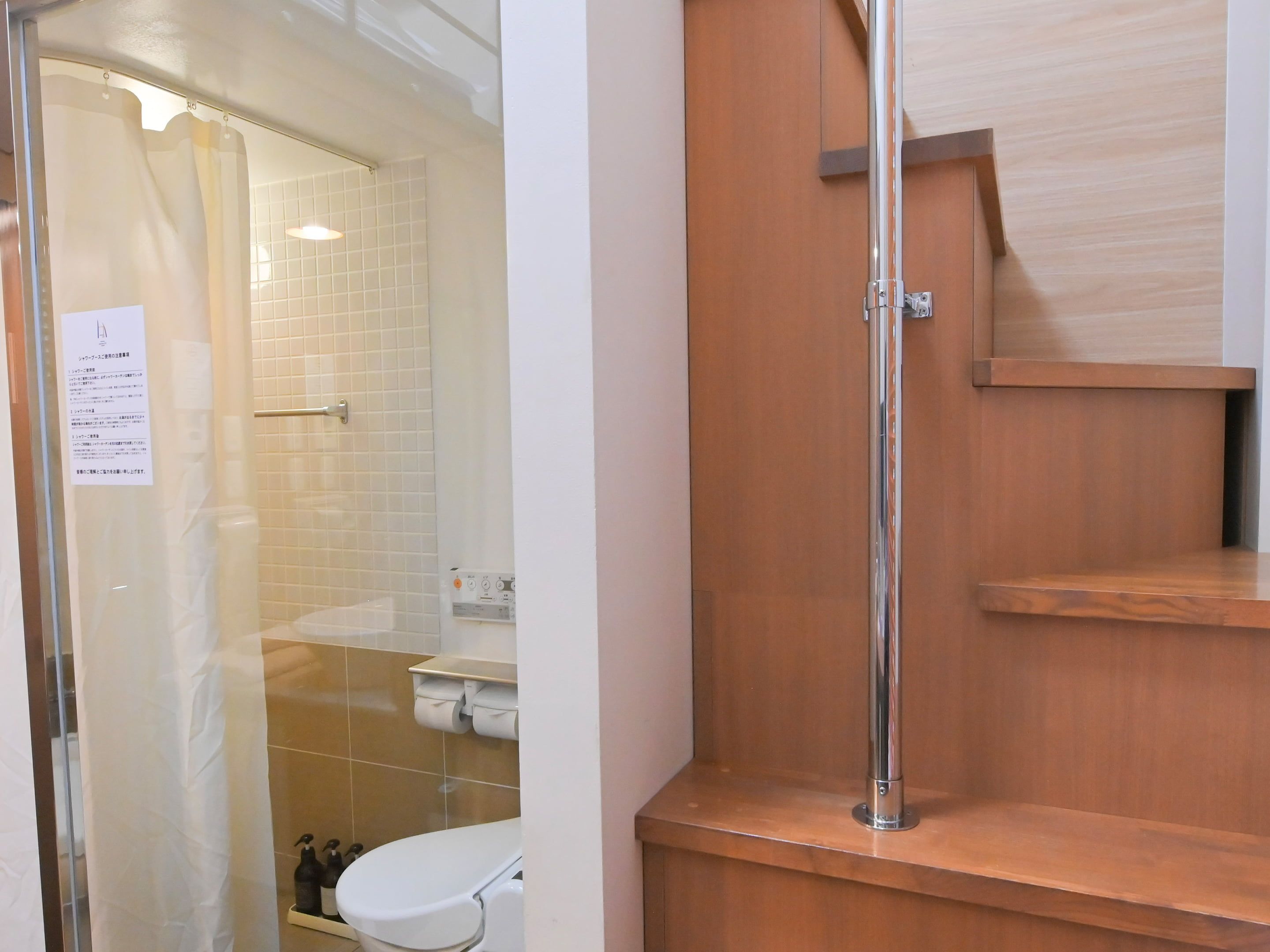 A bathroom with a glass shower enclosure, a toilet, and a wooden vanity with a mirror.