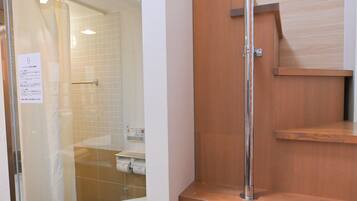 A bathroom with a glass shower enclosure, a toilet, and a wooden vanity with a mirror.