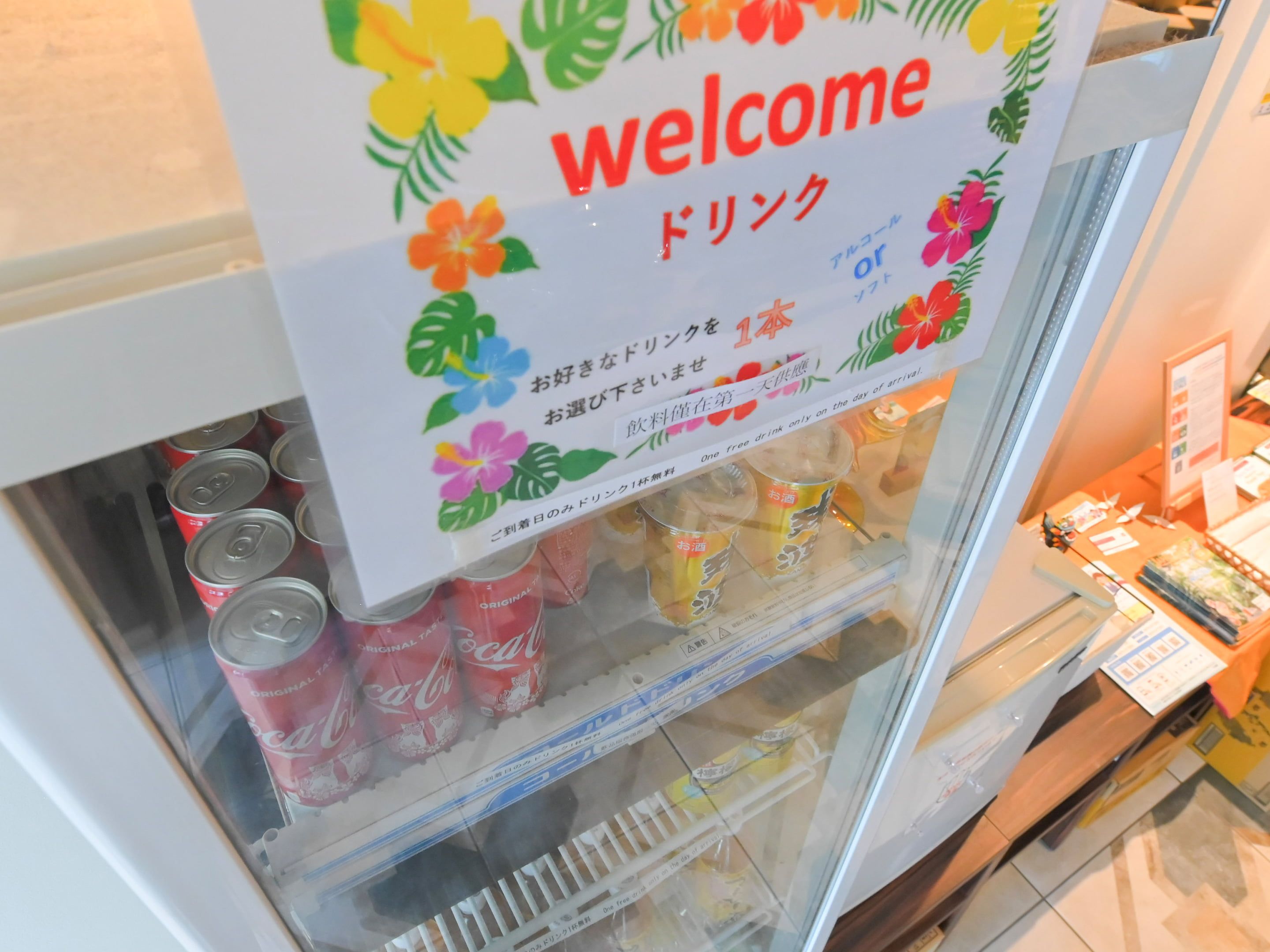 A vending machine with a 'Welcome' sign and a selection of drinks.