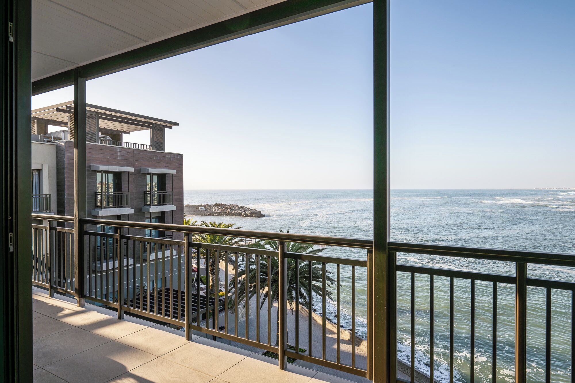 A balcony with a view of the ocean and a rocky shoreline.