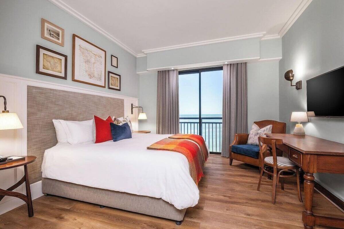 Ein Hotelzimmer mit einem großen Bett, einem Schreibtisch, einem Sessel und einem Fernseher.