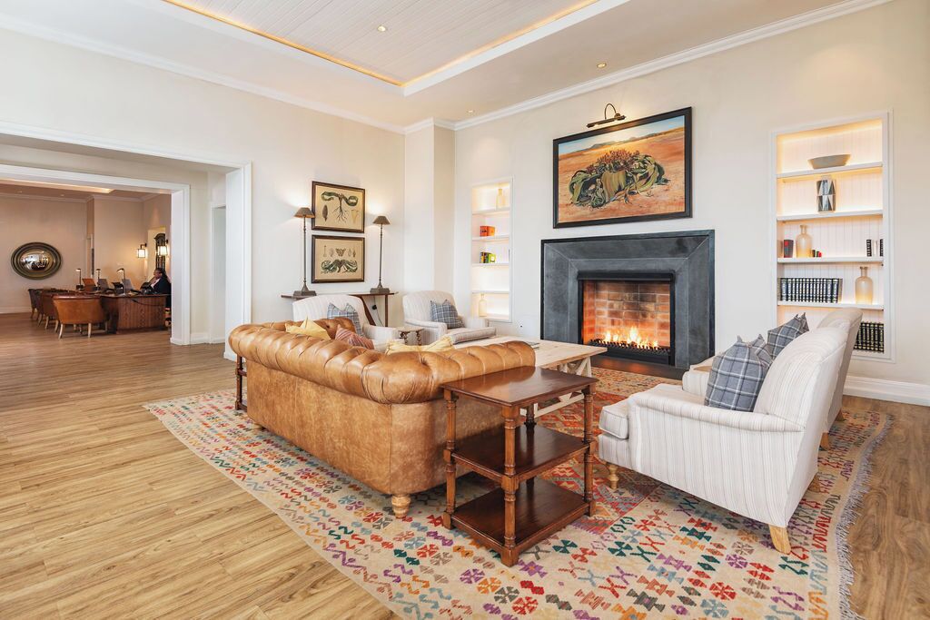 A living room with a fireplace, leather sofa, white armchair, and patterned rug.