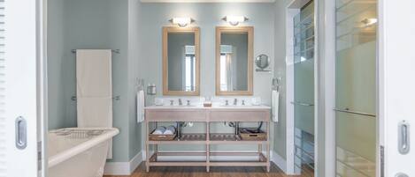 A bathroom with a double vanity, a freestanding bathtub, and a glass shower enclosure.