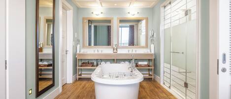 A modern bathroom with a freestanding bathtub, double vanity with mirrors, and a walk-in shower.