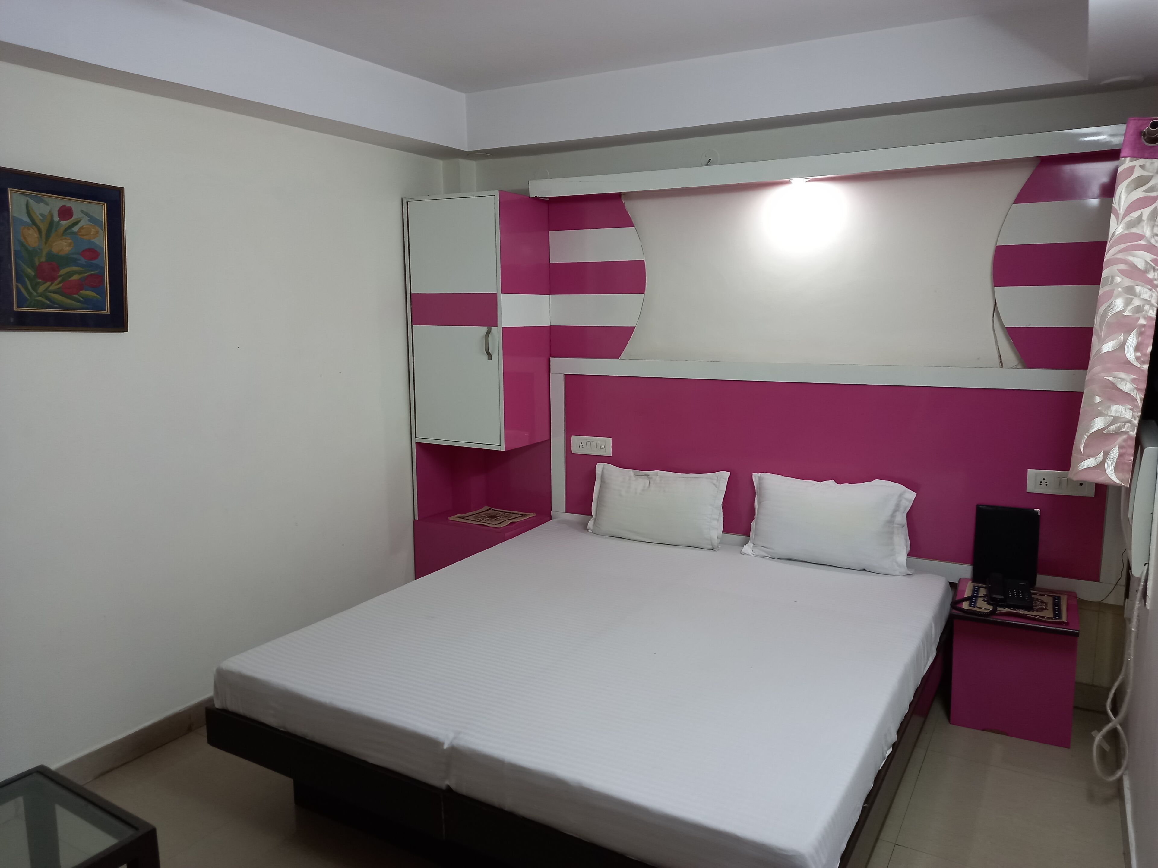 Een kleine, netjes ingerichte slaapkamer met een bed, nachtkastjes, een kledingkast en een wandplank.