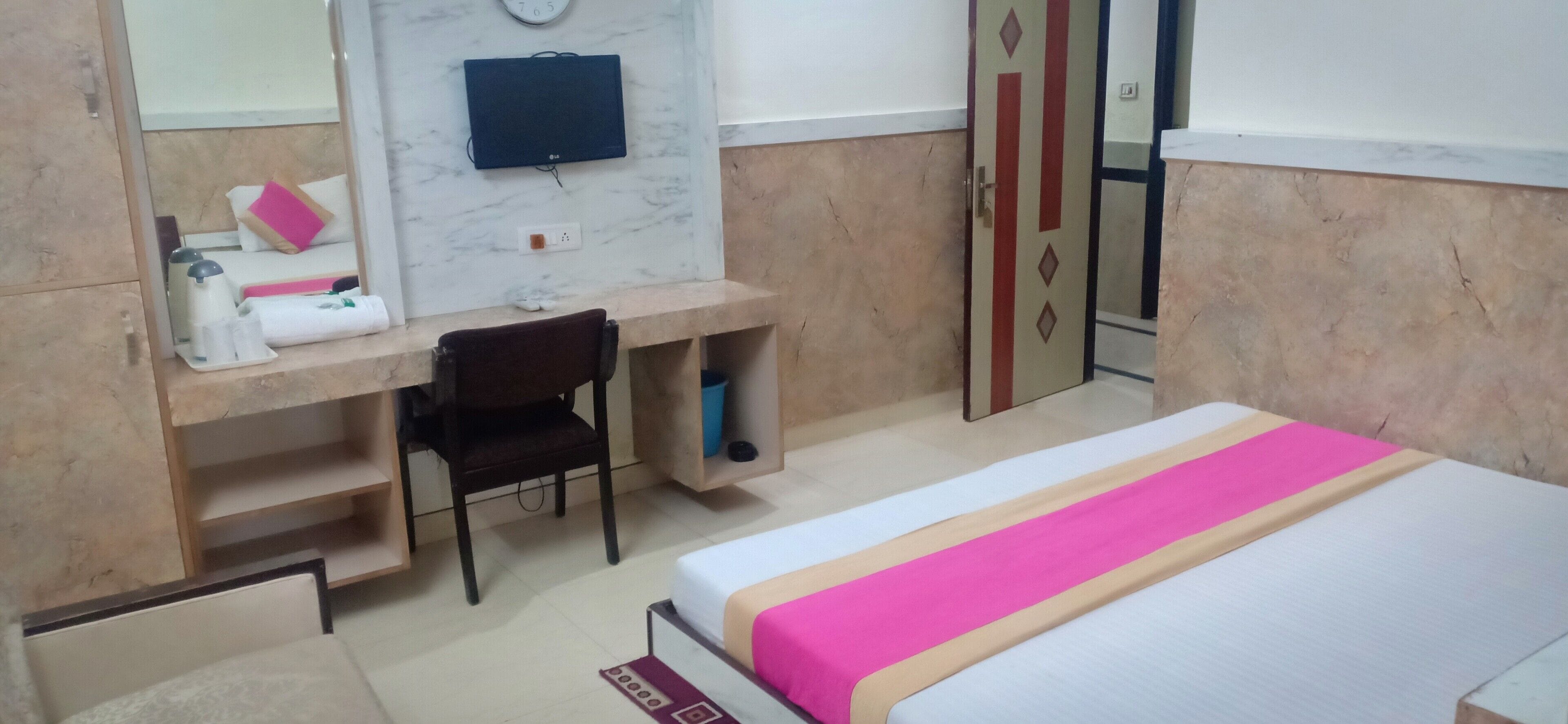 Ein Hotelzimmer mit einem Bett, einem Schreibtisch, einem Sessel, einem Fernseher und einem Kleiderschrank.