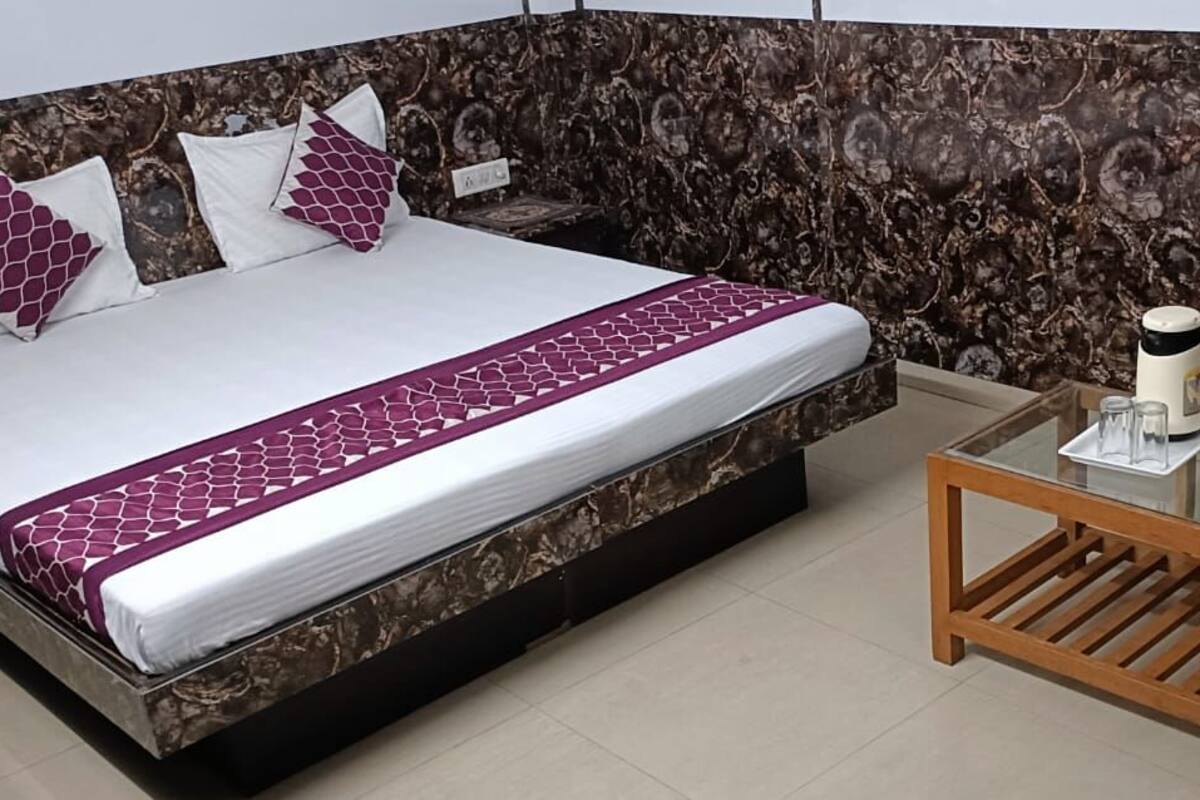 A neatly arranged bedroom with a bed, pillows, a bedside table, and a chair.