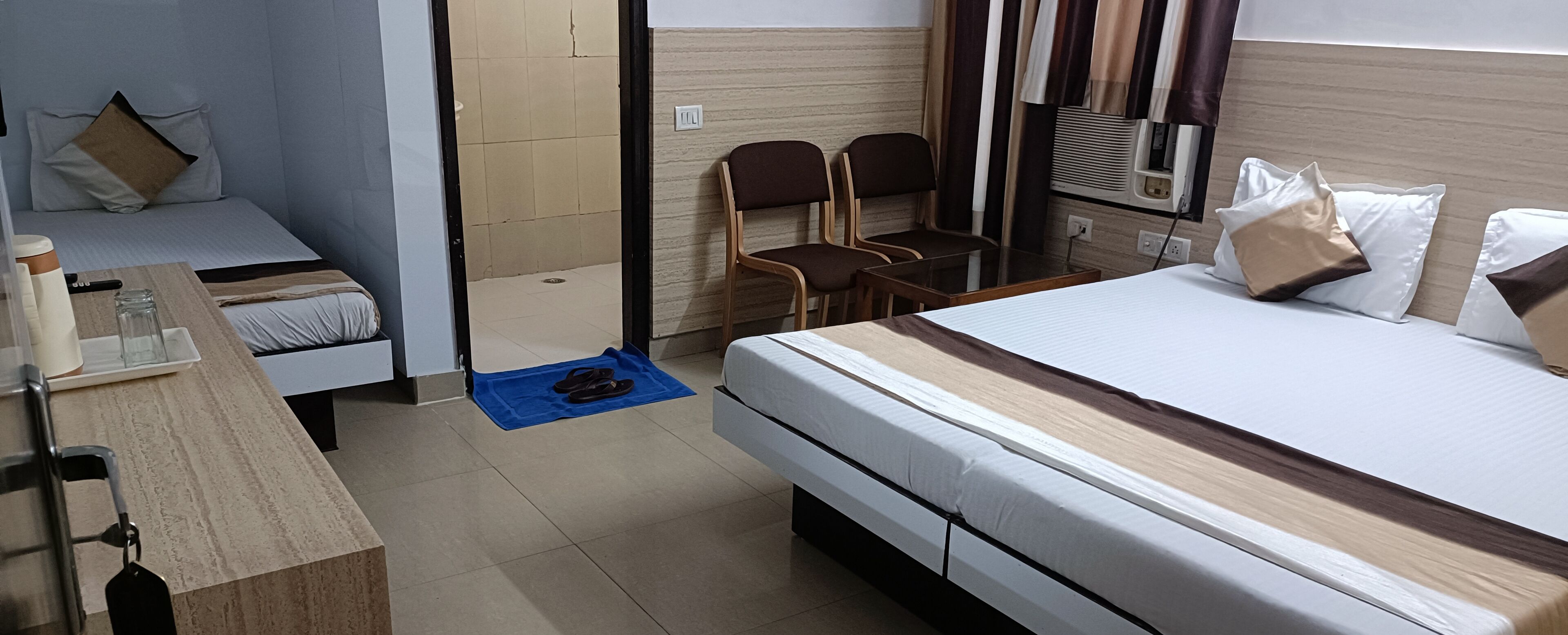 A hotel room with a large bed, a desk with a chair, a small table, and a pair of chairs.