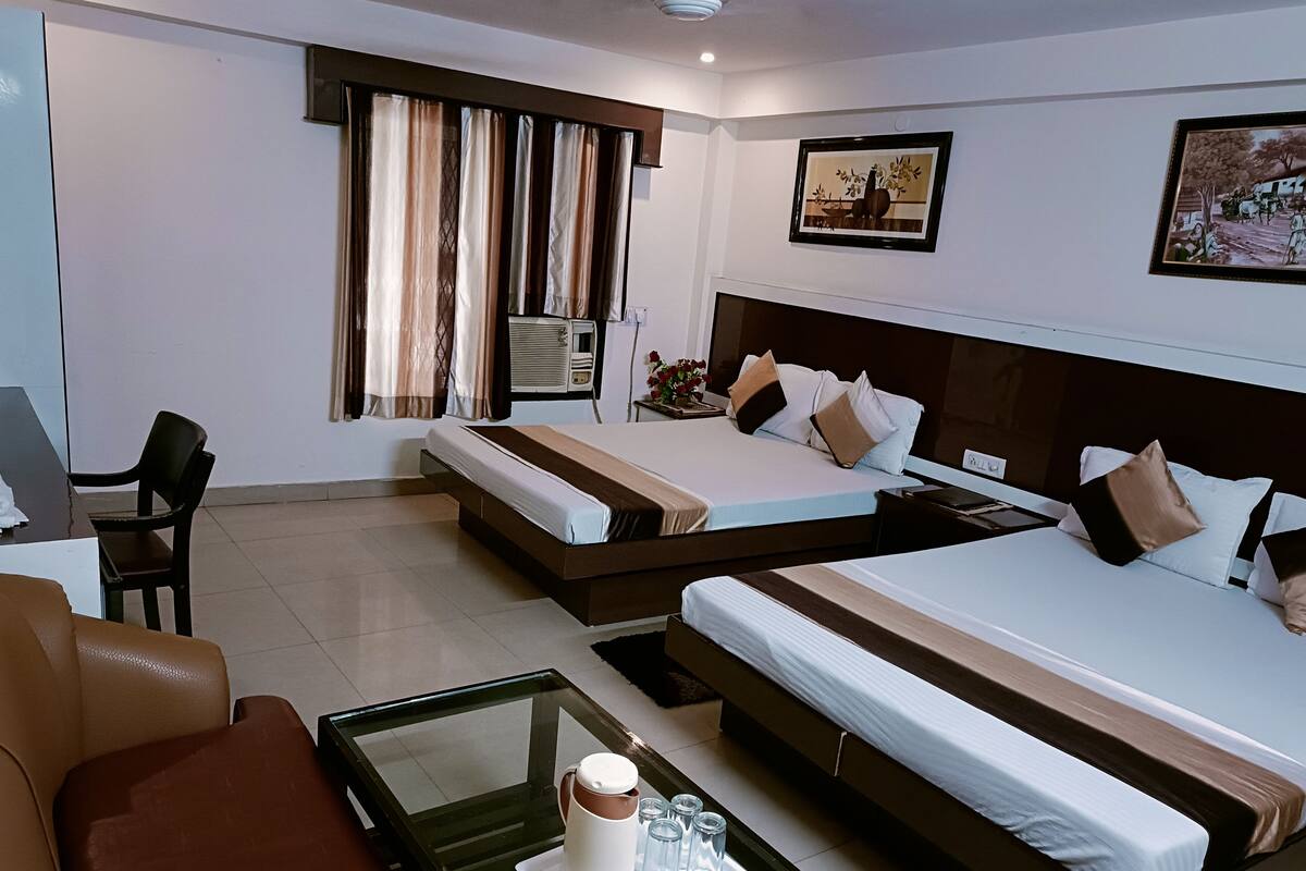 A hotel room with two beds, a desk, a chair, and a coffee table.