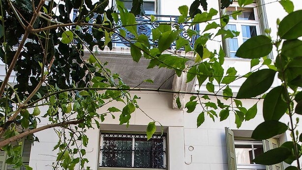 A building with a green door, a balcony, and a potted plant in front.
