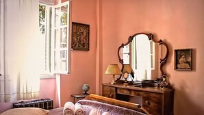 A bedroom with a bed, a dresser, a mirror, and a window with curtains.