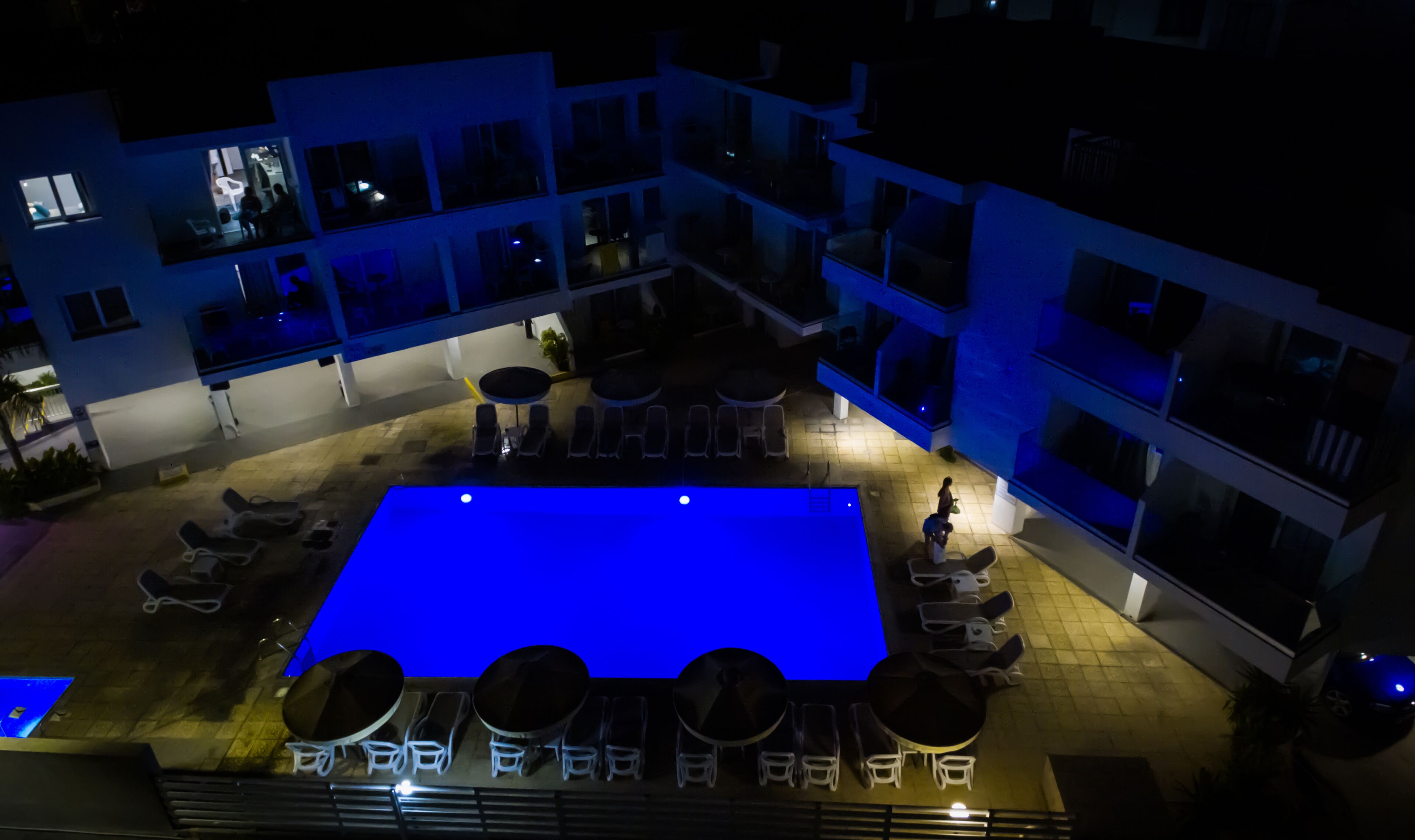 A rooftop pool area with lounge chairs and a blue pool.