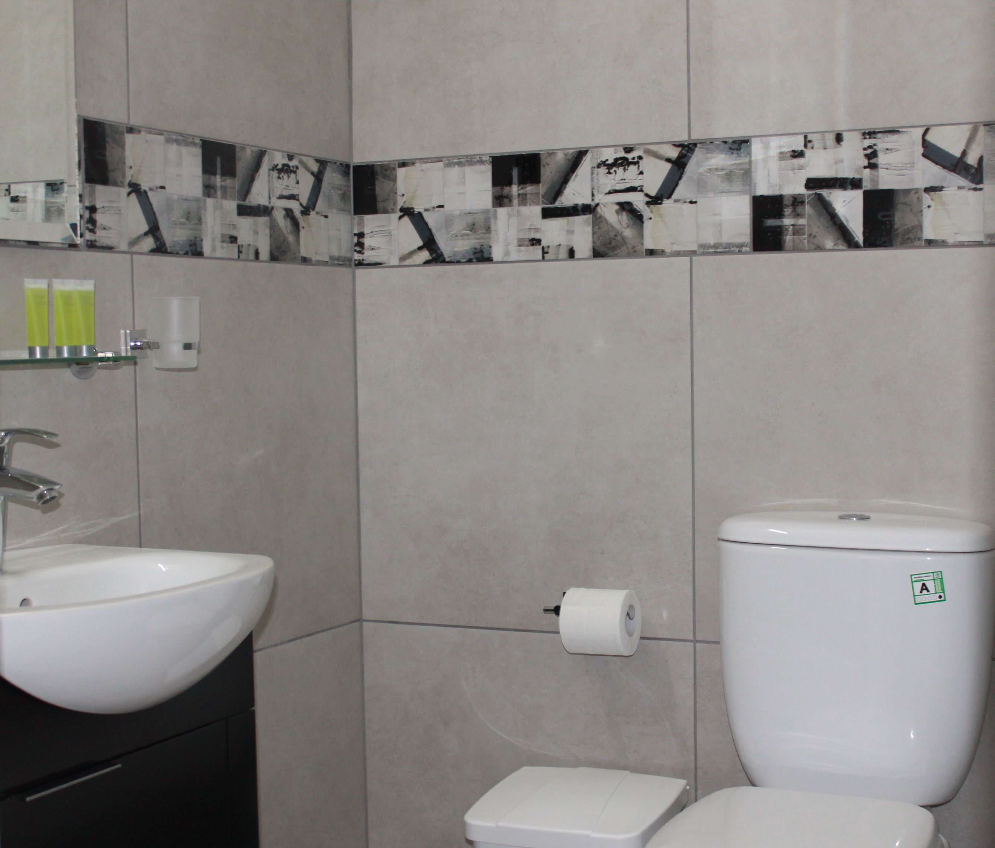 Ein Badezimmer mit einem weißen Waschbecken, einer Toilette und einer kleinen Mülleimer.