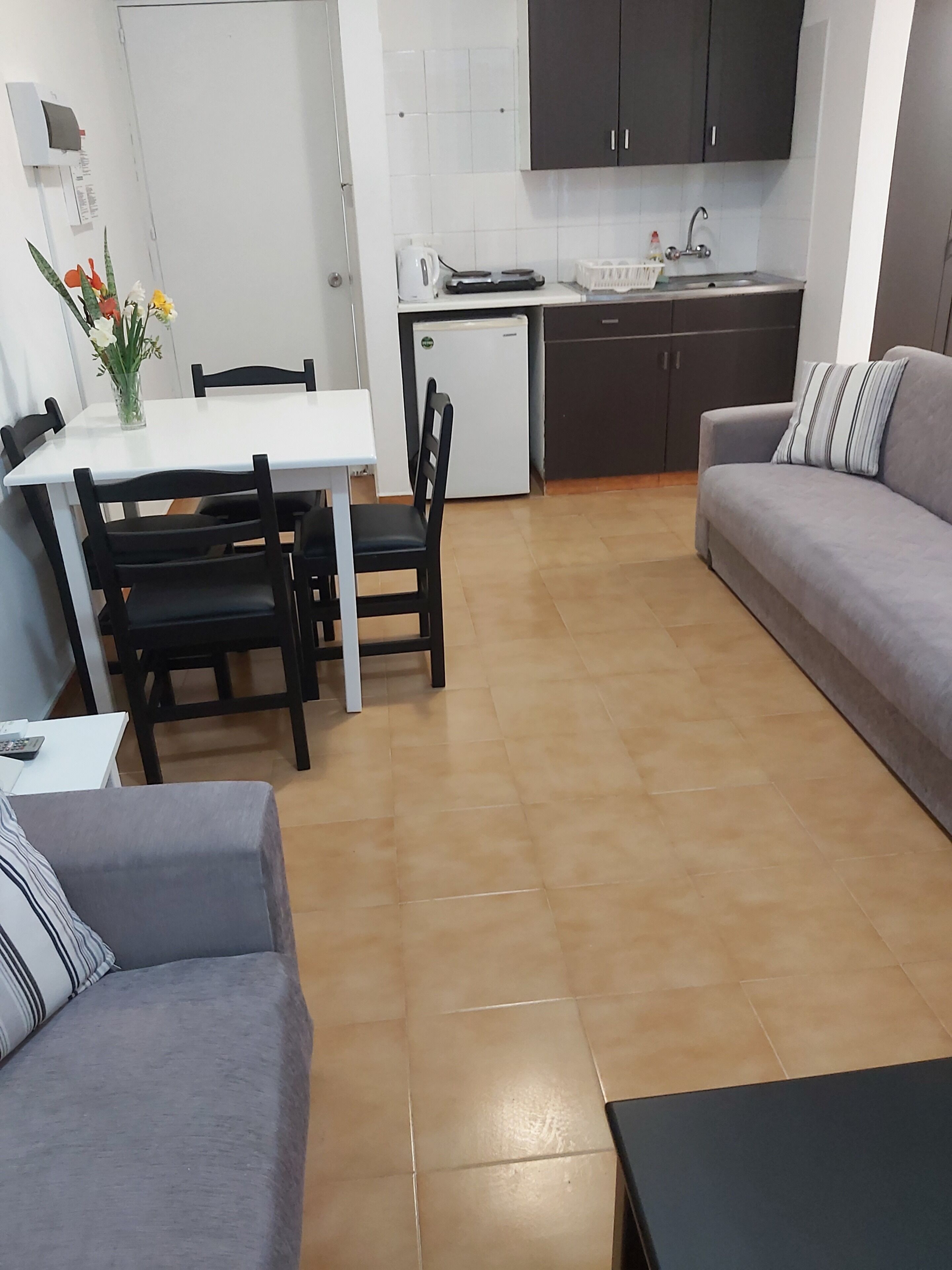 Ett kompakt bostadsutrymme med en matplats, ett litet kök och en soffa.