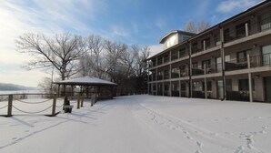 A snow-covered courtyard with a wooden gazebo and a multi-story building with balconies. - Paddle Wheel Inn (Oregon)
