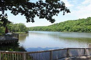 A calm river with a wooden dock and a bridge.