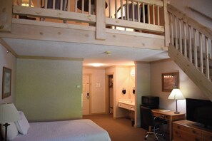A hotel room with a bed, desk, chair, television, and a staircase. - Paddle Wheel Inn (Oregon)